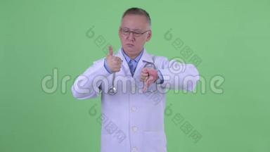 成熟的日本男医生在竖起大拇指和大拇指之间做出选择